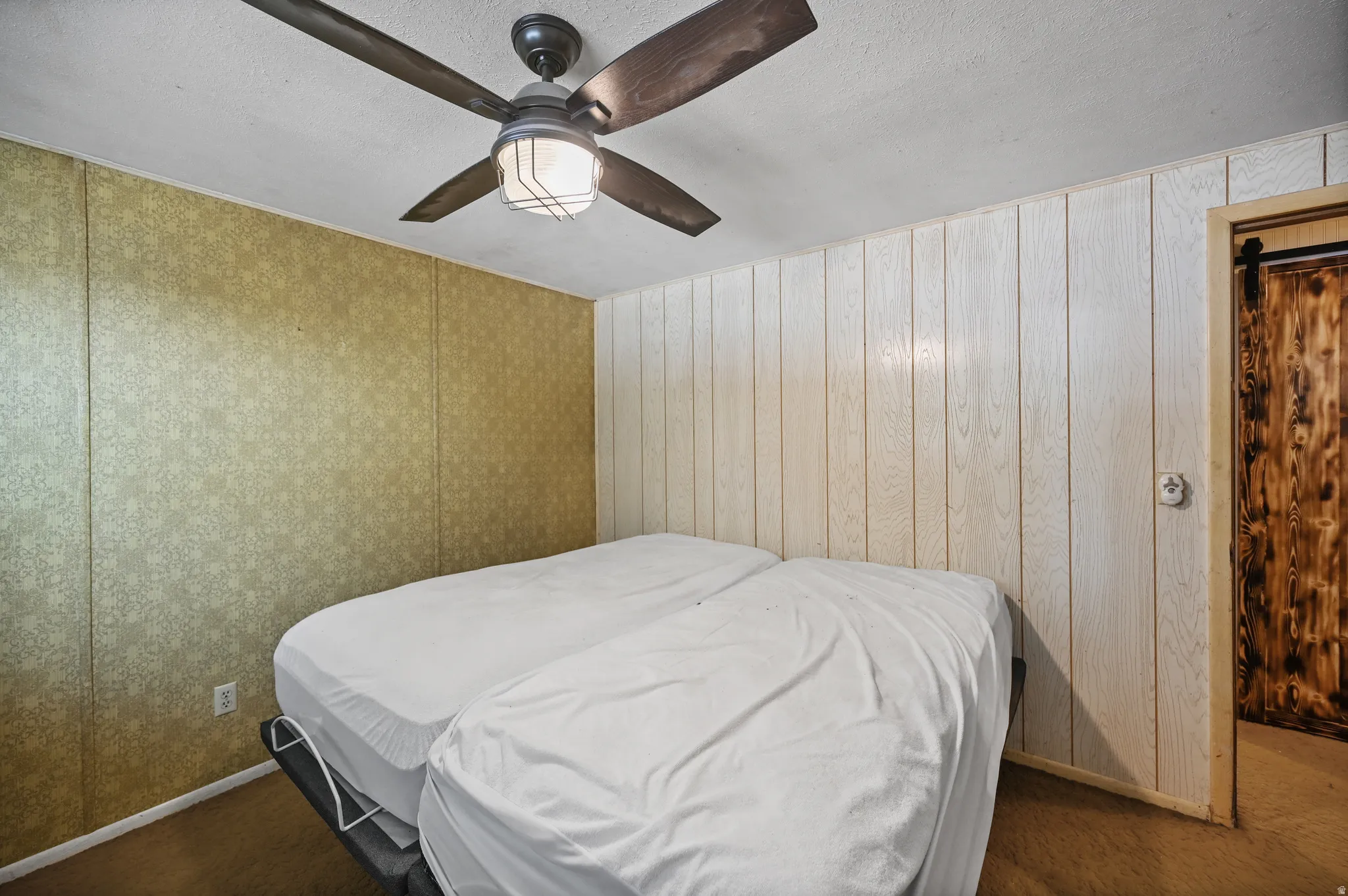 Carpeted bedroom featuring ceiling fan and a textured ceiling