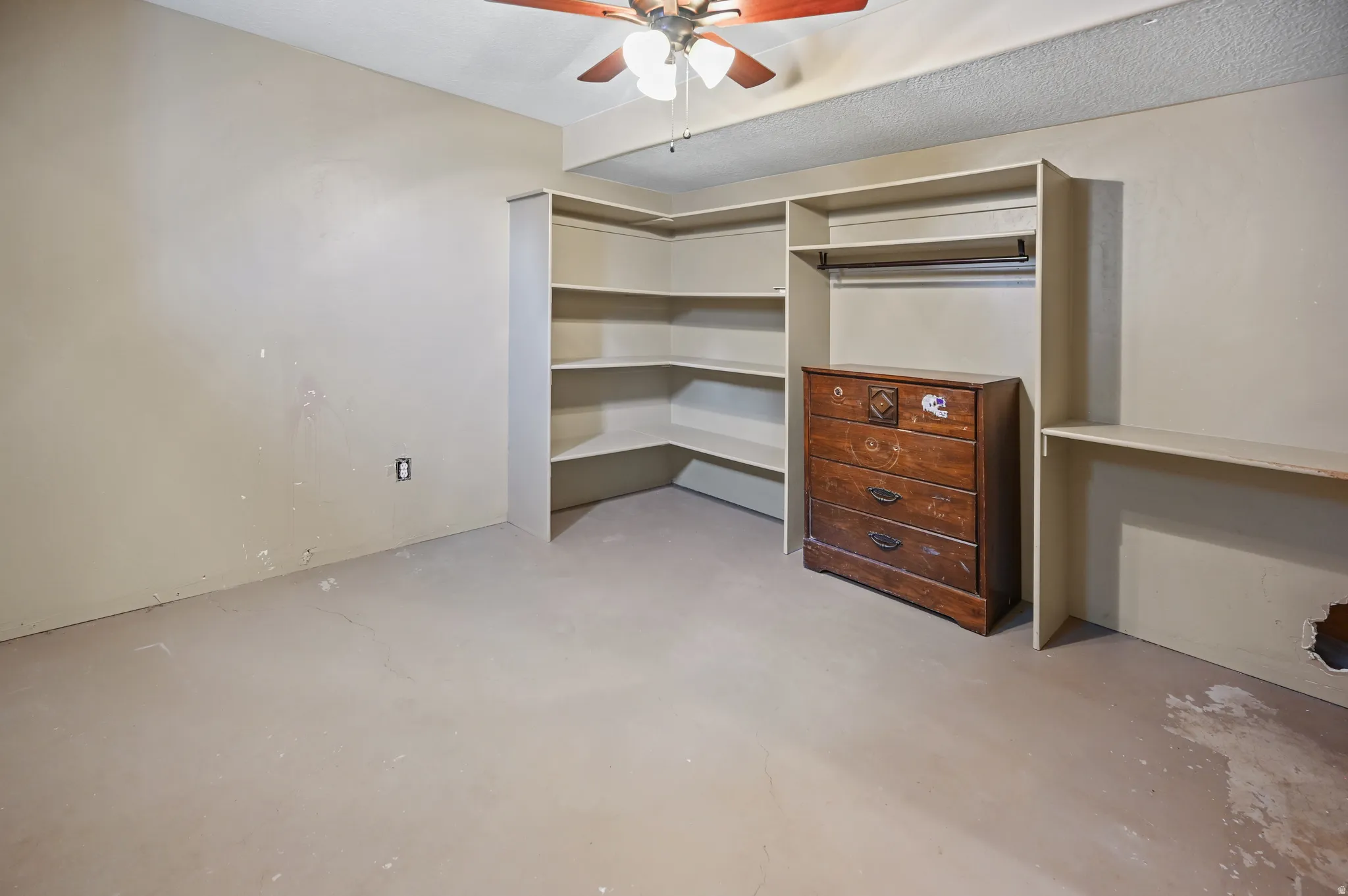 Unfurnished bedroom with concrete flooring, ceiling fan, and a closet