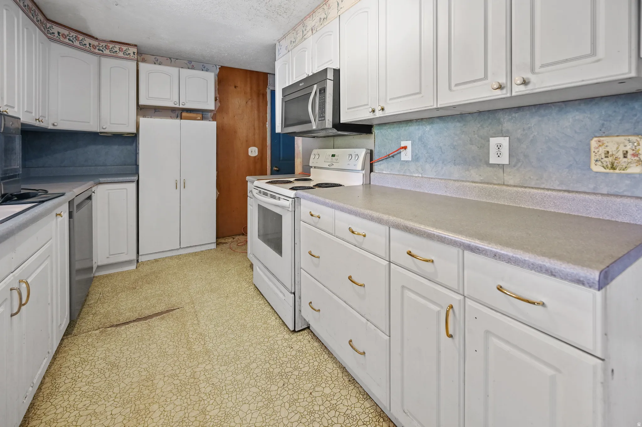 Kitchen featuring white cabinets, light floors, stainless steel appliances, and light countertops