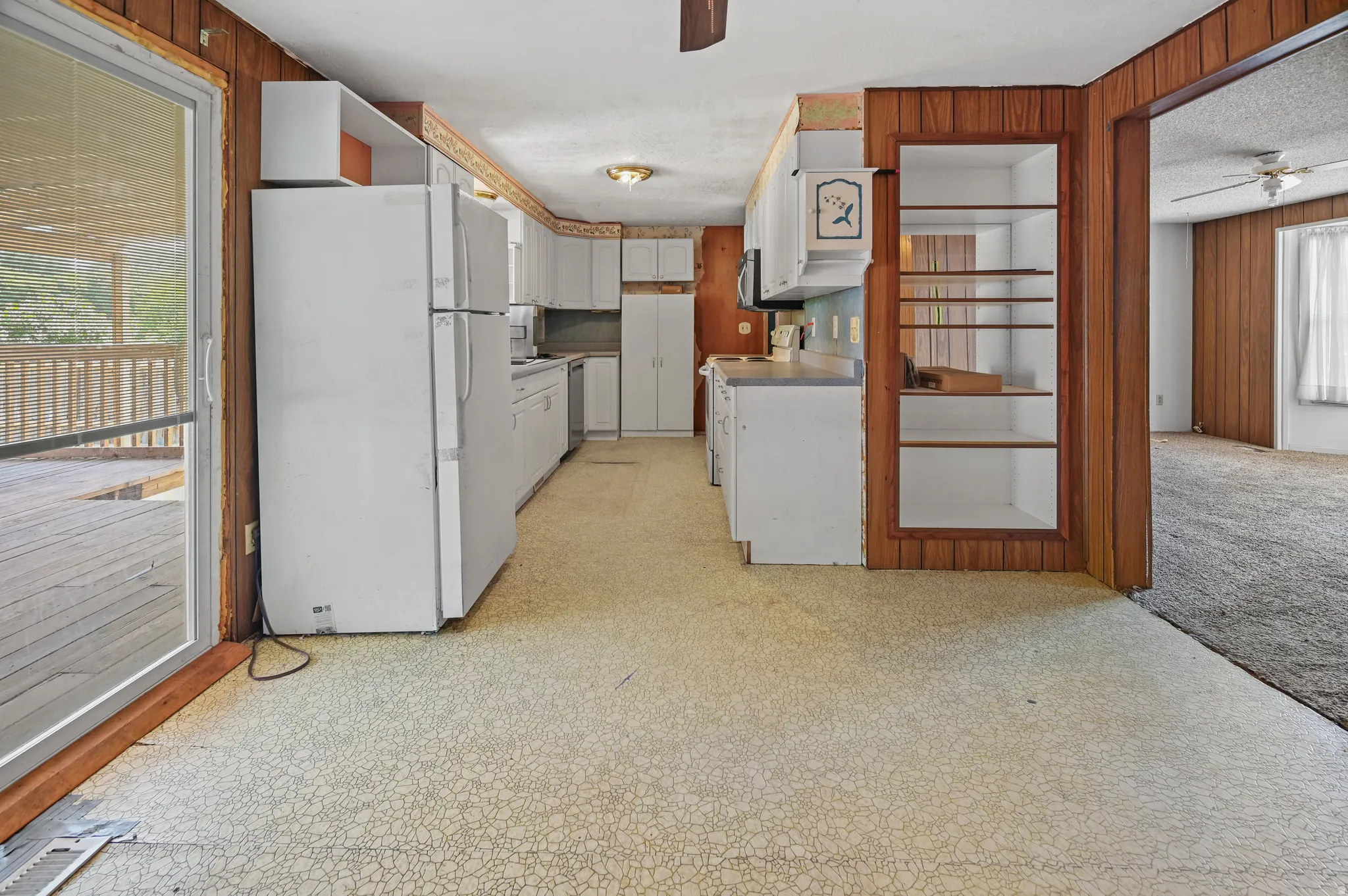 Kitchen featuring a ceiling fan, white appliances, light flooring, and white cabinetry