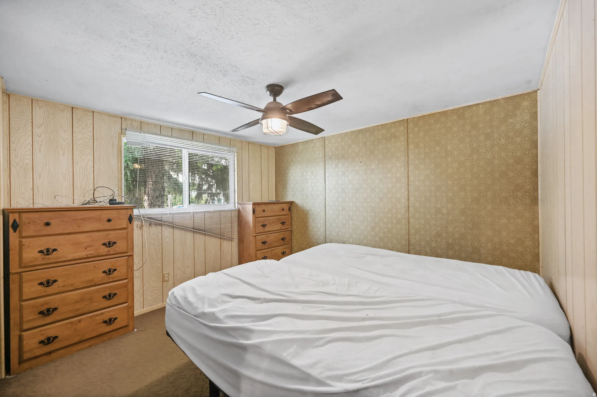 Carpeted bedroom featuring a ceiling fan and a textured ceiling