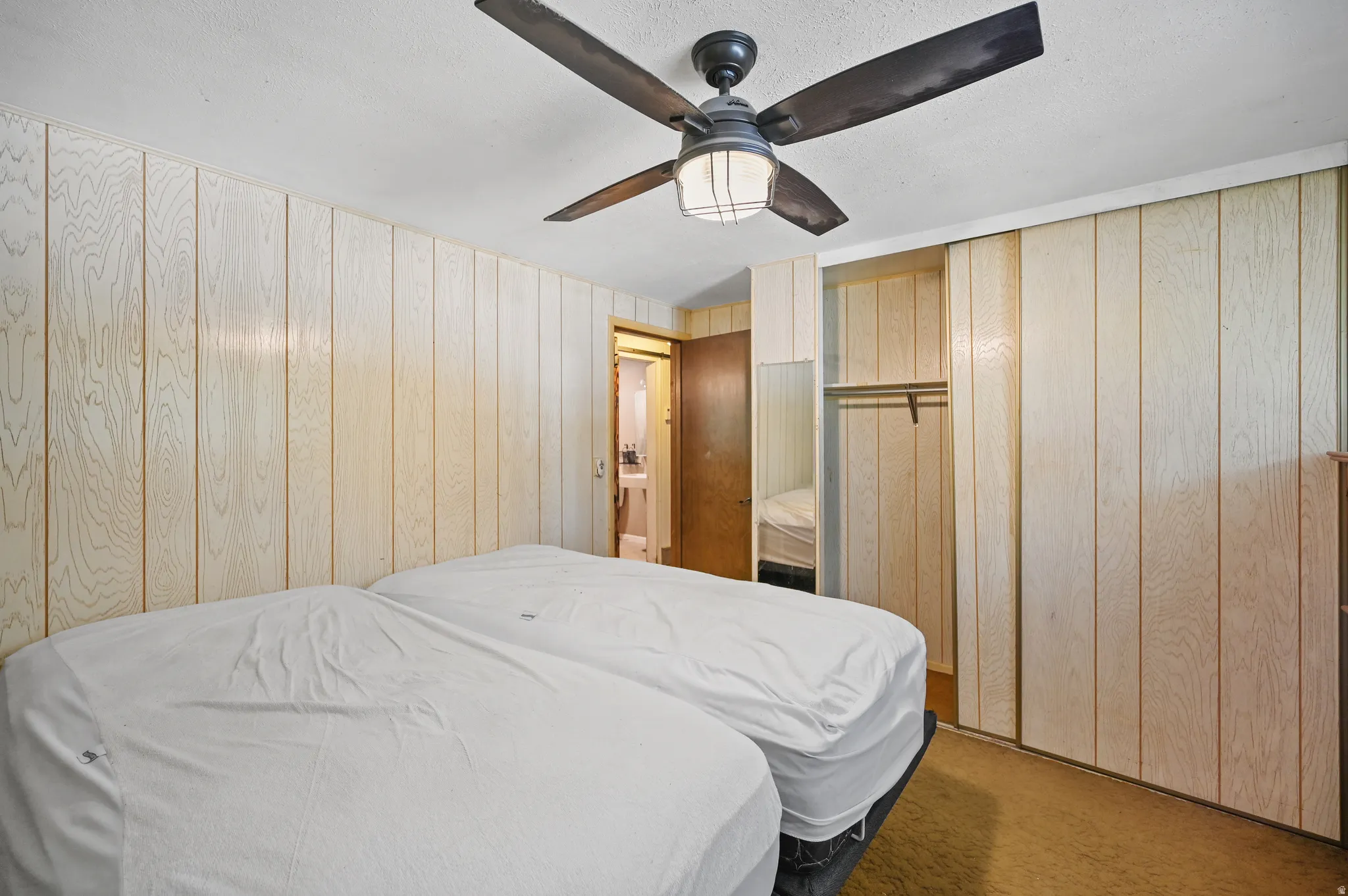 Carpeted bedroom featuring a ceiling fan and wood walls