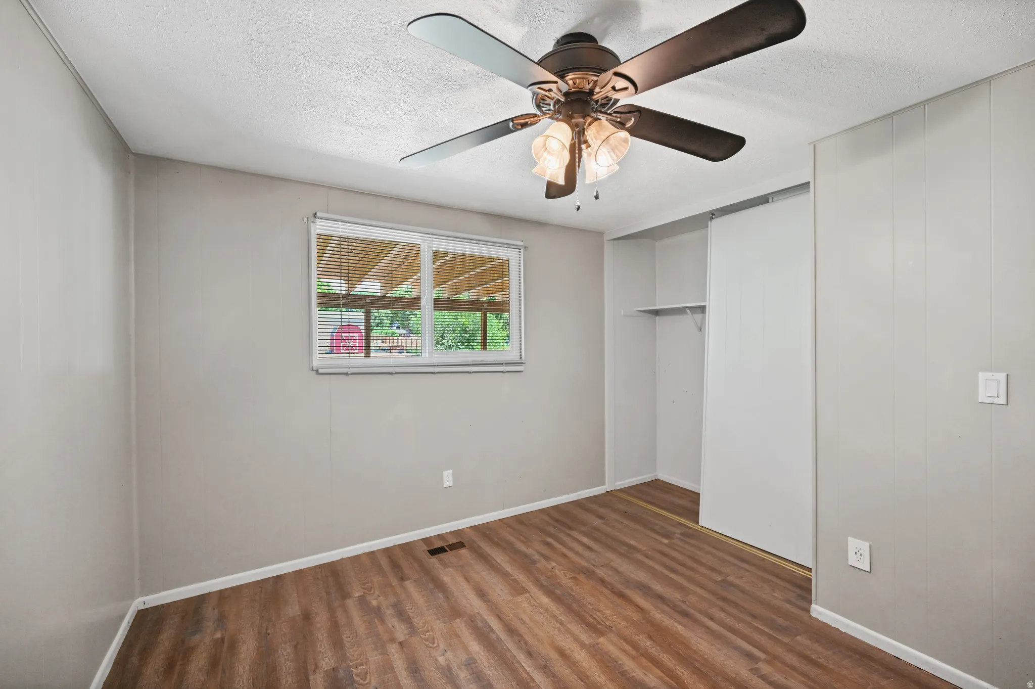 Unfurnished bedroom featuring a closet, dark wood-type flooring, ceiling fan, and a textured ceiling