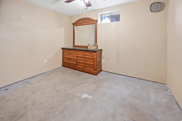 Unfurnished room with unfinished concrete flooring and a ceiling fan