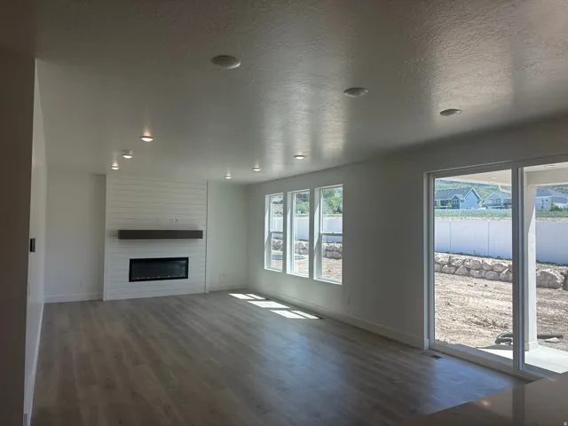 Living area with wood-finish flooring, recessed lighting, and a shiplap feature wall with an electric fireplace