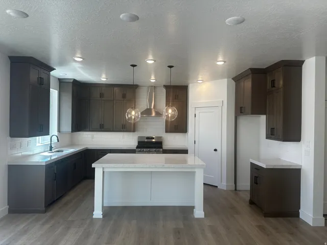 Modern kitchen featuring dark wood-finish cabinetry, light stone-finish countertops, and a white subway tile backsplash