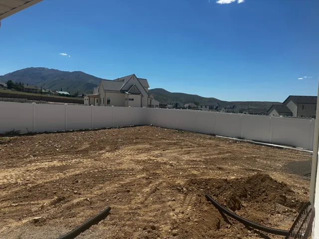 Expansive graded lot featuring a durable vinyl privacy fence