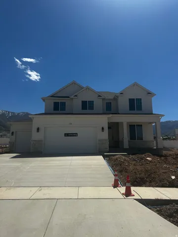 Modern two-story residence with a three-car garage, stone accents, and a covered porch entry