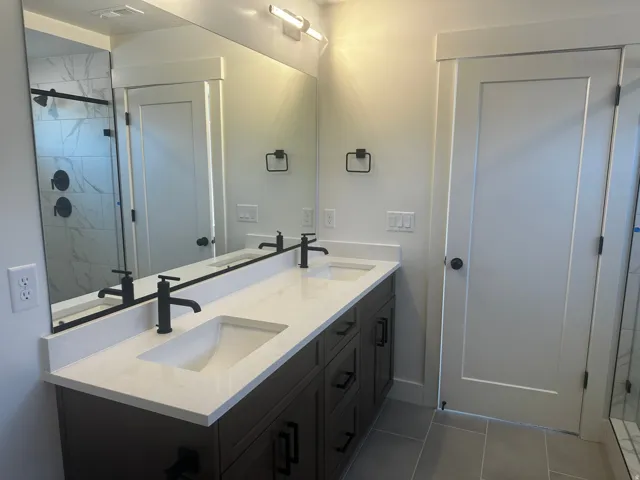 Dual vanity with integrated rectangular sinks, white countertop, dark wood-finish cabinetry, and matte black fixtures