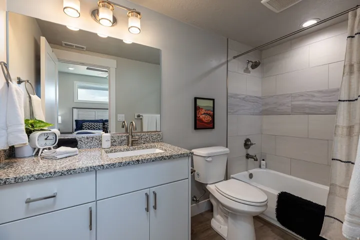 Bathroom featuring shower / bathtub combination with curtain, vanity, dark wood-style flooring, and recessed lighting