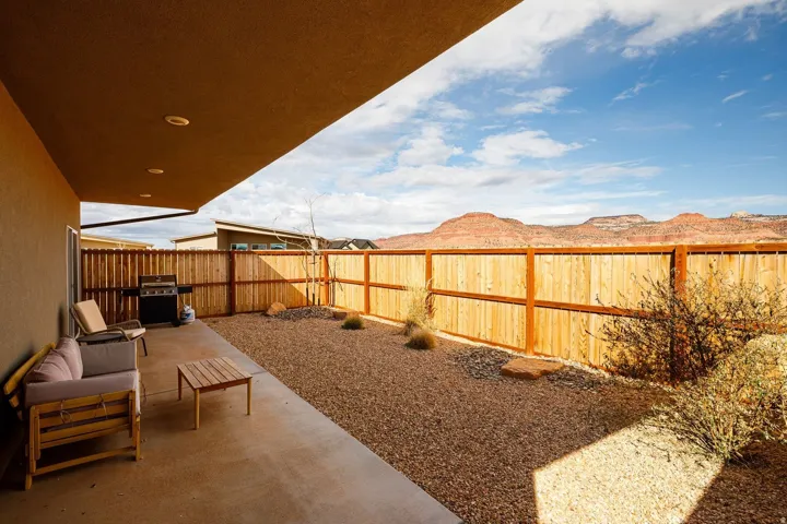 Fenced backyard featuring a patio area and a grill