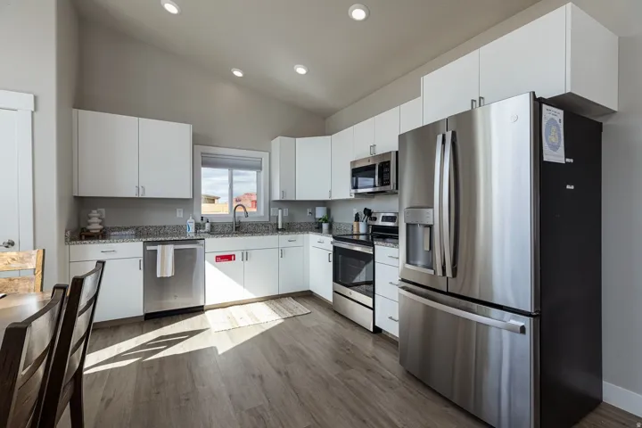 Kitchen with stainless steel appliances, white cabinetry, lofted ceiling, dark wood finished floors, and recessed lighting