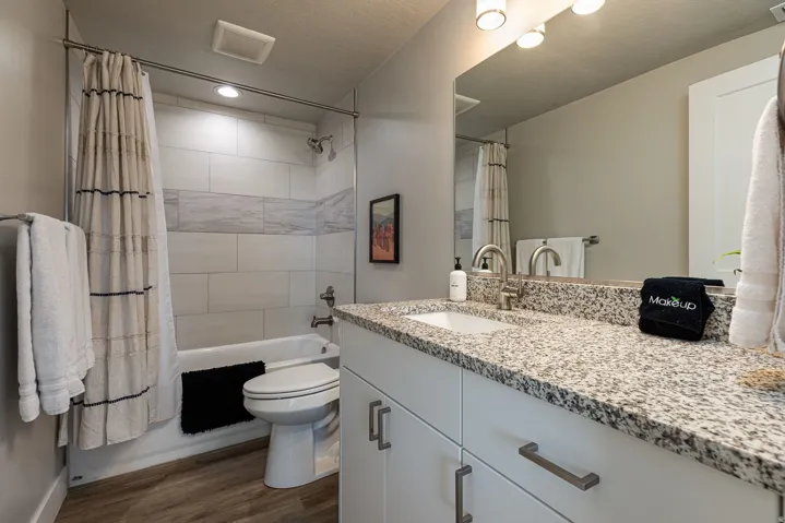 Full bathroom with vanity, shower / bath combo with shower curtain, dark wood finished floors, and a textured ceiling