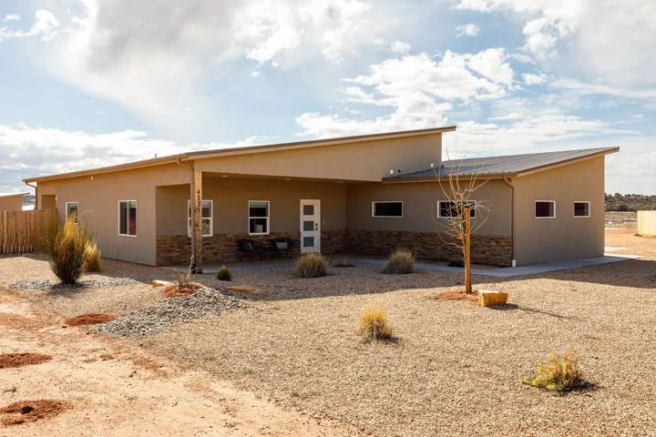 Back of house featuring stone siding, a patio, and stucco siding