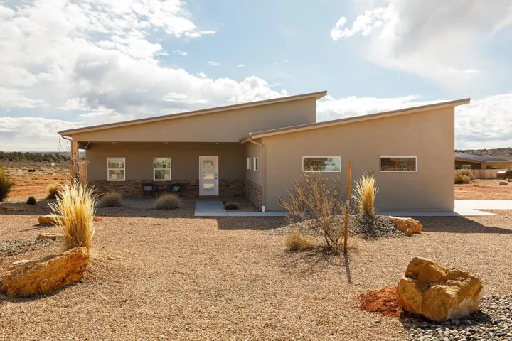 Rear view of property with a patio area, stucco siding, and stone siding