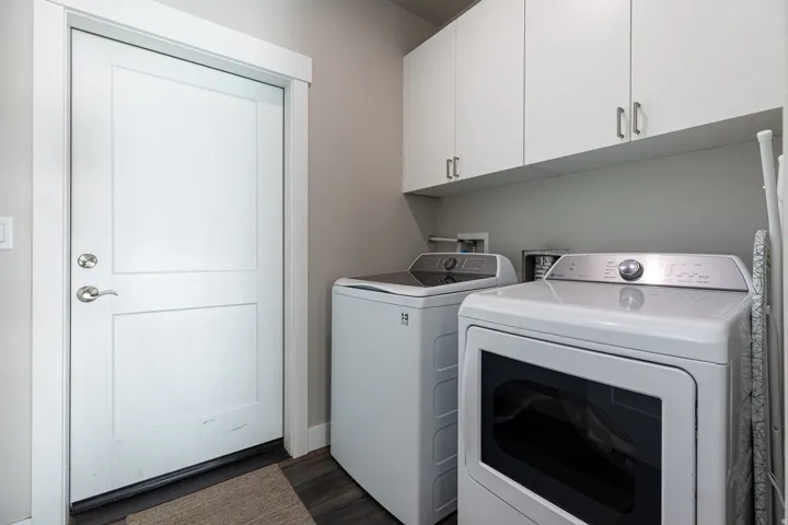 Laundry area featuring independent washer and dryer, cabinet space, and dark wood-type flooring