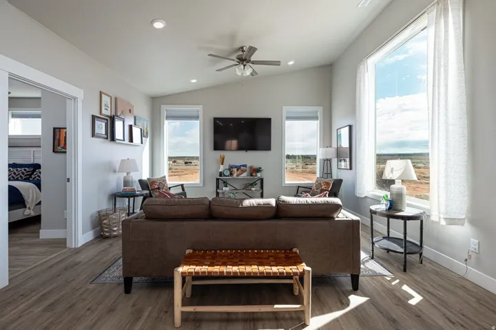 Living room with ceiling fan, wood finished floors, healthy amount of natural light, lofted ceiling, and recessed lighting