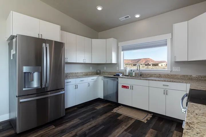 Kitchen featuring stainless steel appliances, white cabinetry, light stone countertops, lofted ceiling, and recessed lighting