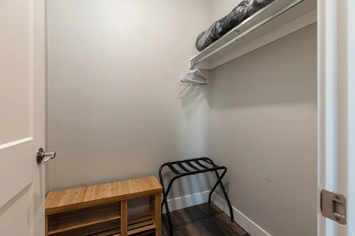 Walk in closet with dark wood-type flooring
