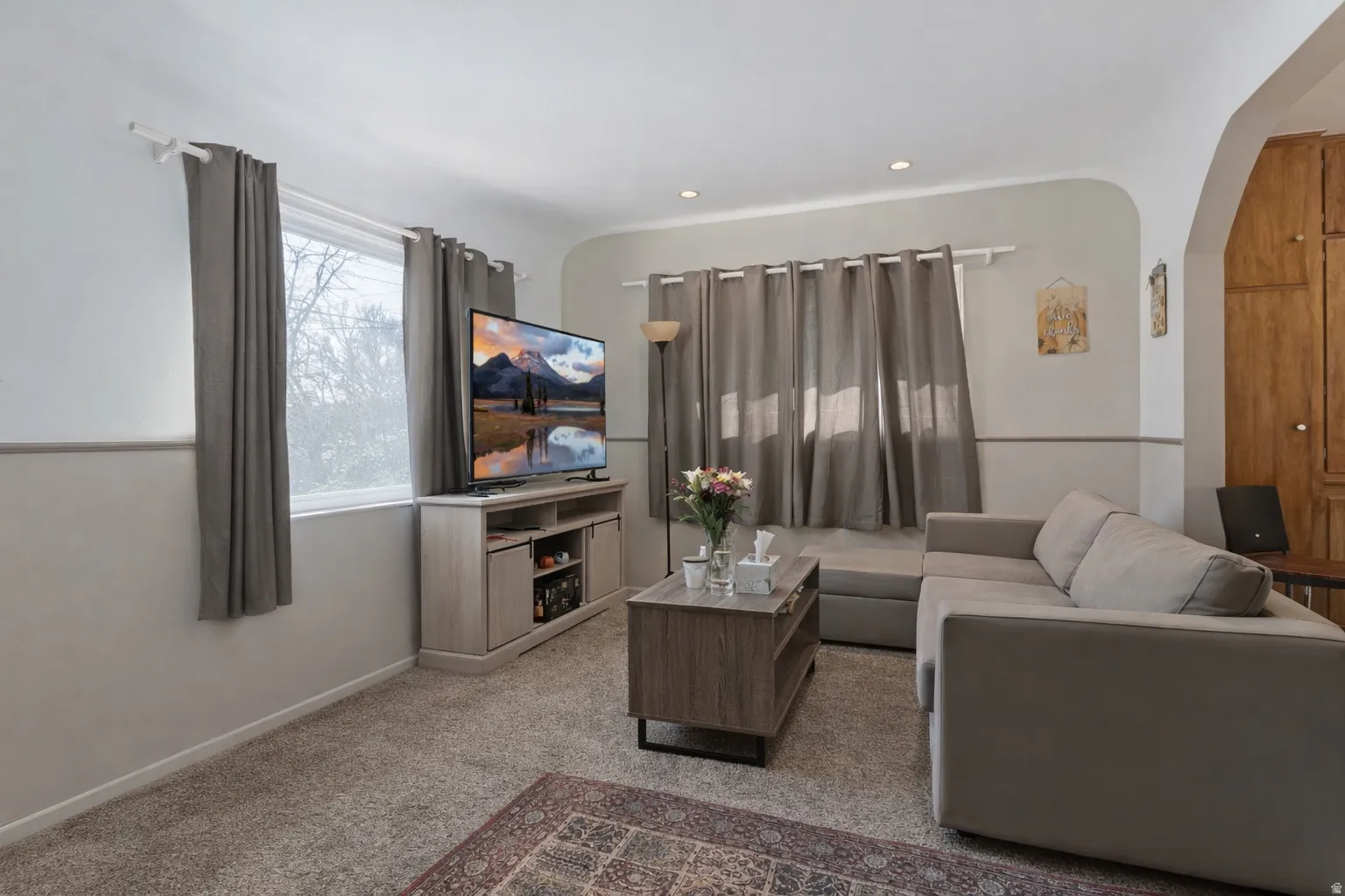 Living area with arched walkways, light carpet, and recessed lighting