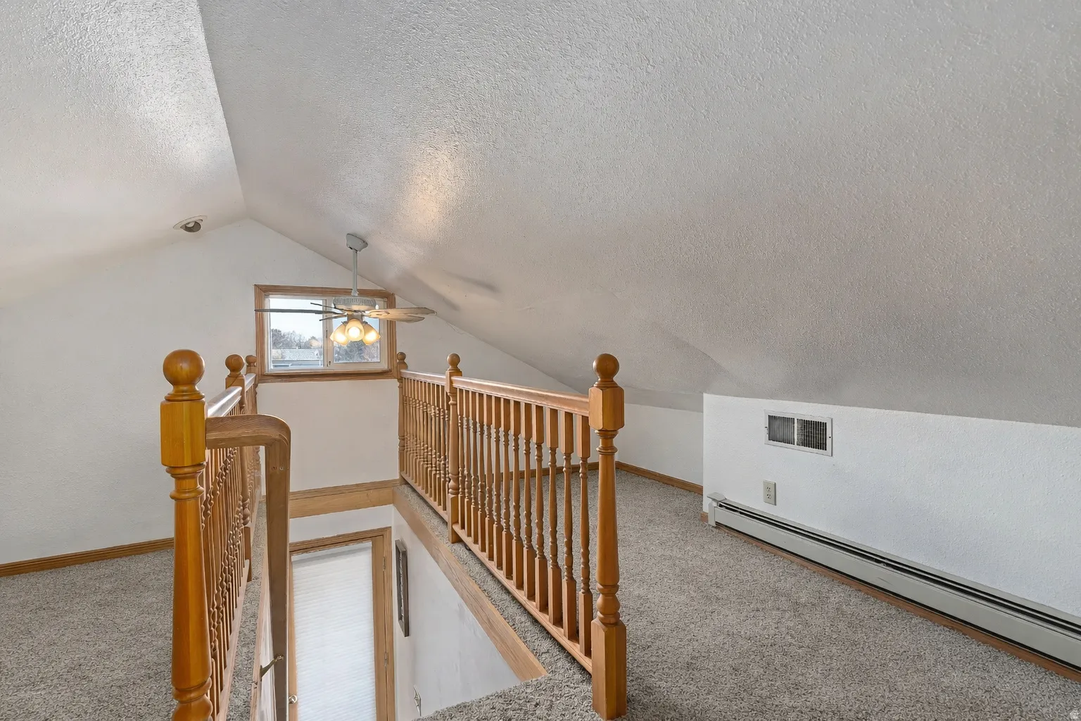 Bonus room featuring carpet floors, baseboard heating, and a textured ceiling