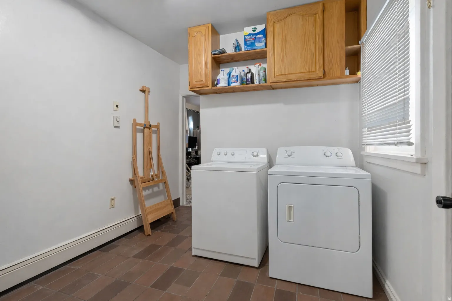 Laundry area featuring a baseboard heating unit, separate washer and dryer, and cabinet space