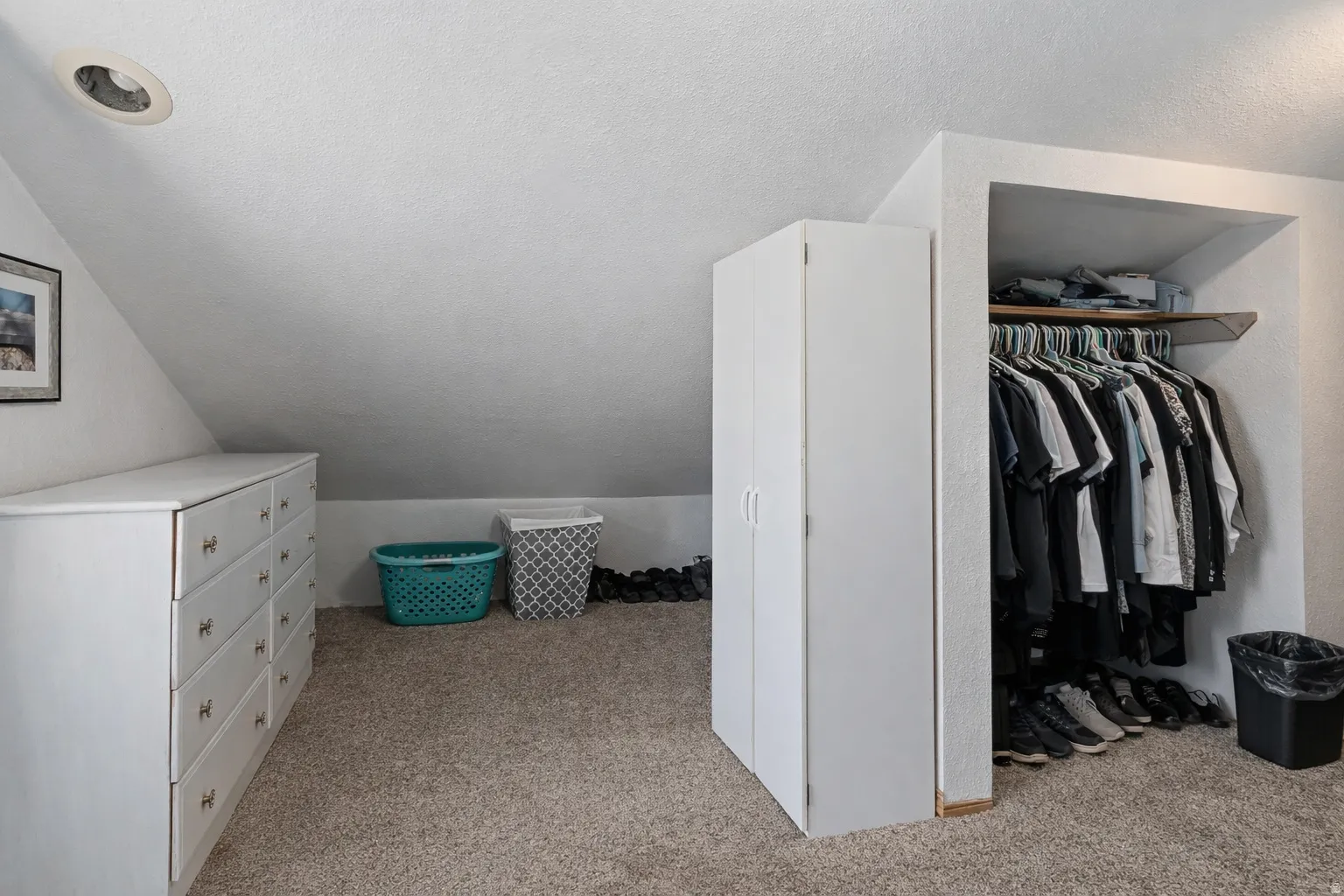 Walk in closet with light carpet and lofted ceiling