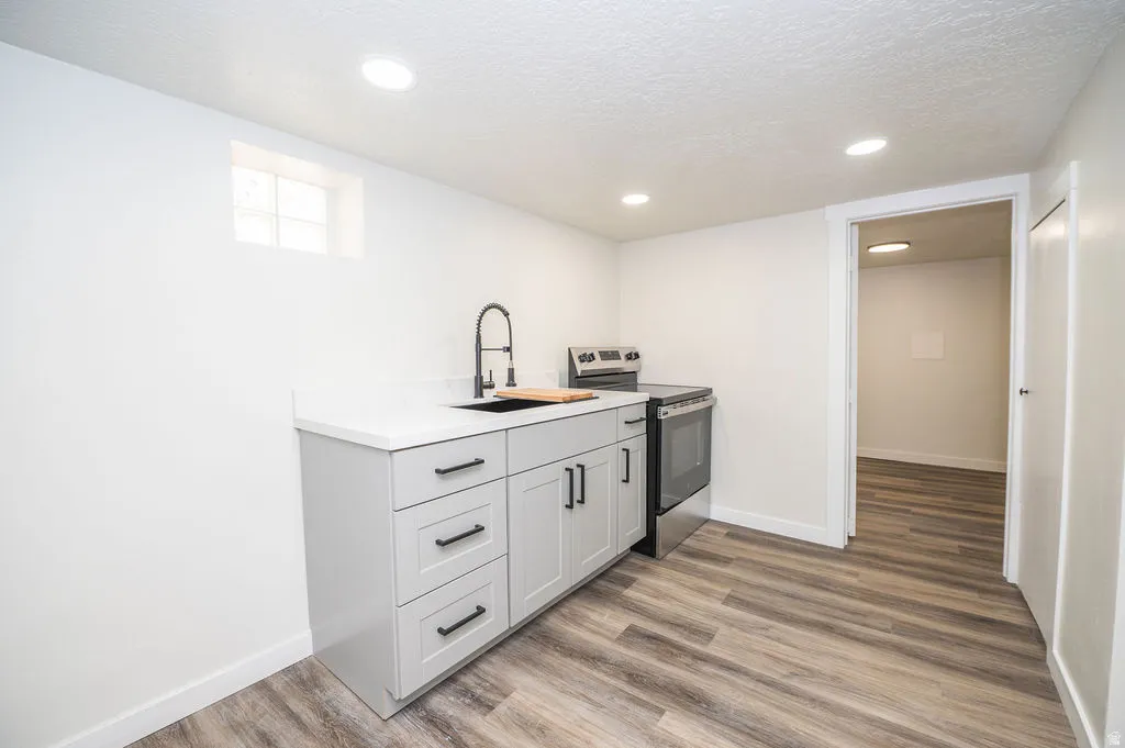 Kitchen with electric stove, gray cabinetry, a textured ceiling, light wood-style floors, and recessed lighting