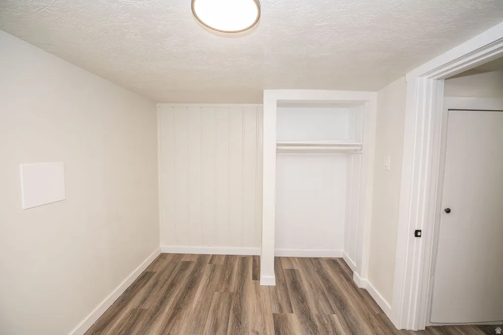 Unfurnished bedroom with a textured ceiling, dark wood finished floors, and a closet