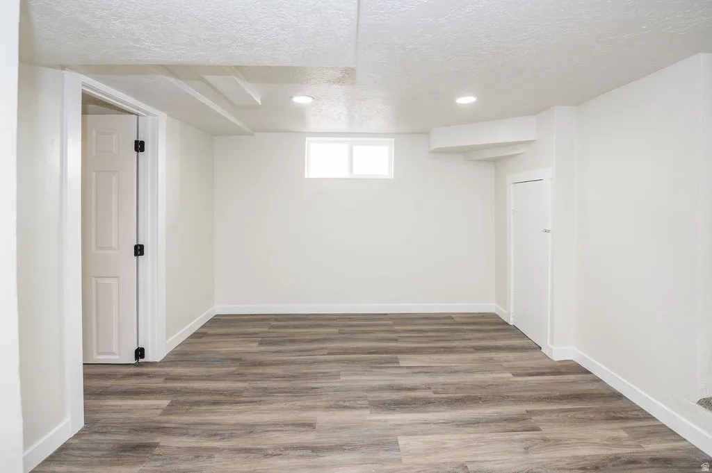 Basement with a textured ceiling, wood finished floors, and recessed lighting