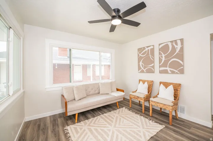 Living area featuring dark wood-style flooring, a ceiling fan, and a textured ceiling