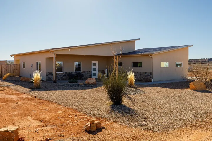 Rear view of house with stone siding, stucco siding, and a patio area