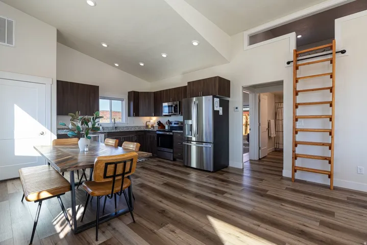 Kitchen with dark wood finish cabinetry, stainless steel appliances, dark wood-style floors, lofted ceiling, and recessed lighting