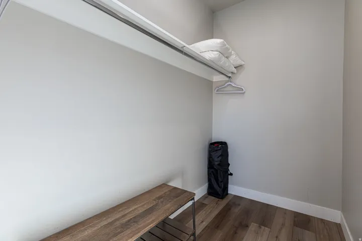 Walk in closet with dark wood-type flooring