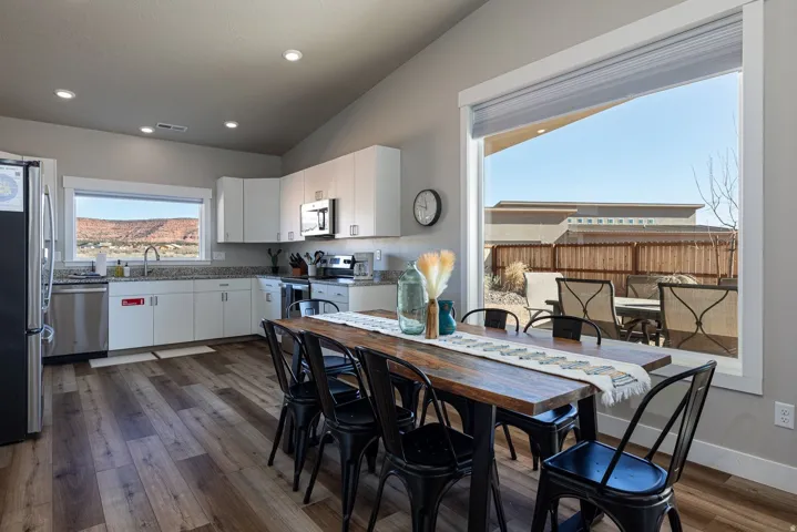 Dining room featuring vaulted ceiling, dark wood-style flooring, and recessed lighting