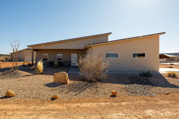 Rear view of property with stucco siding, a patio, and stone siding