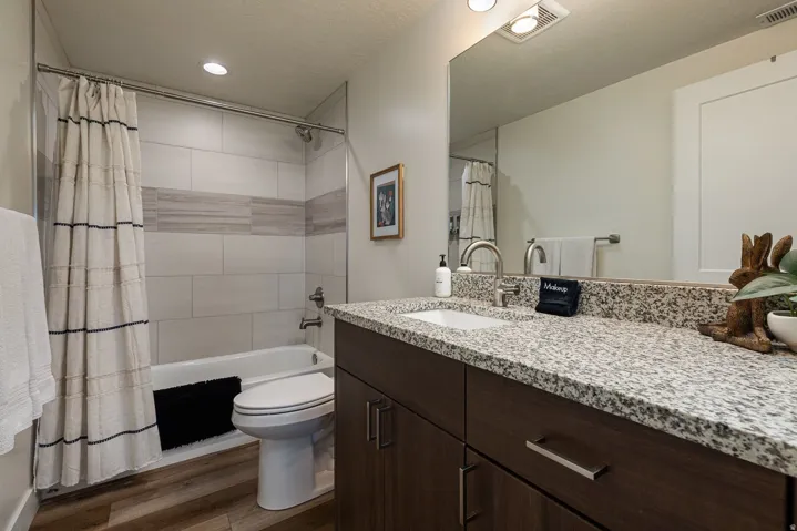 Full bath with shower / bathtub combination with curtain, vanity, dark wood-type flooring, a textured ceiling, and recessed lighting