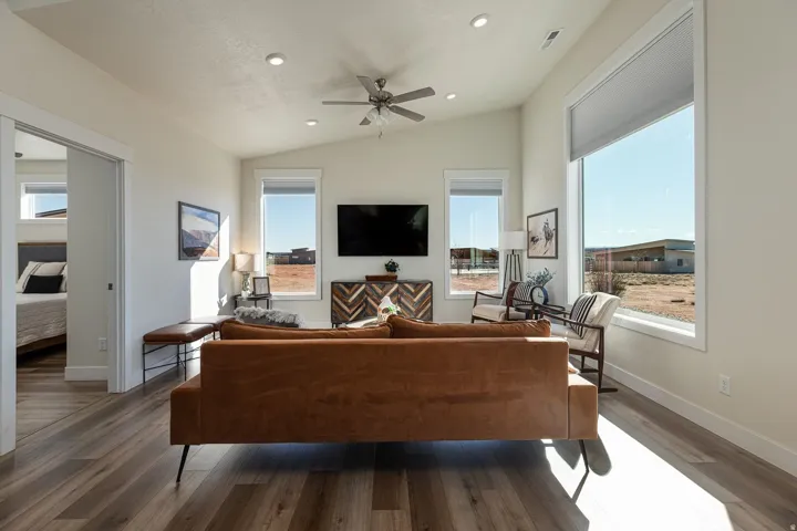 Living room featuring lofted ceiling, a ceiling fan, hardwood / wood-style flooring, healthy amount of natural light, and recessed lighting