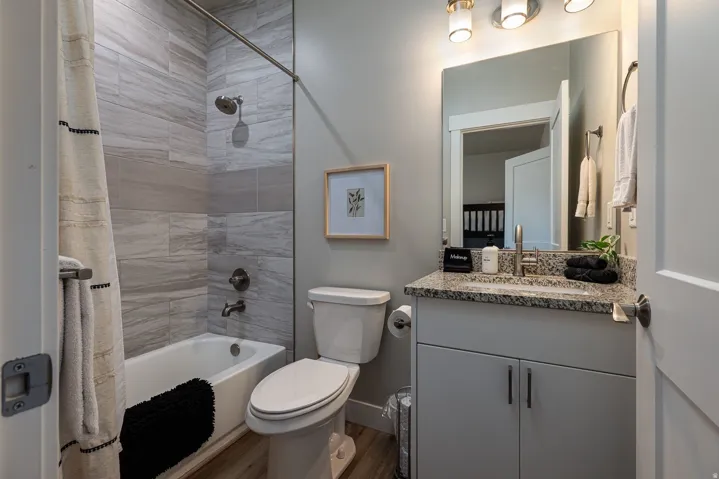 Full bath featuring shower / tub combo, vanity, and dark wood-style flooring