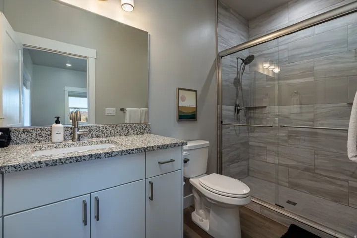 Full bath featuring vanity, a shower stall, and wood finished floors