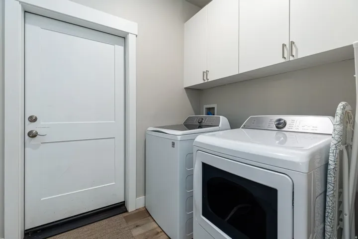 Laundry area with wood finished floors, washing machine and clothes dryer, and cabinet space