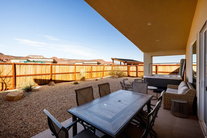 Fenced backyard featuring a patio, outdoor dining area, and a hot tub