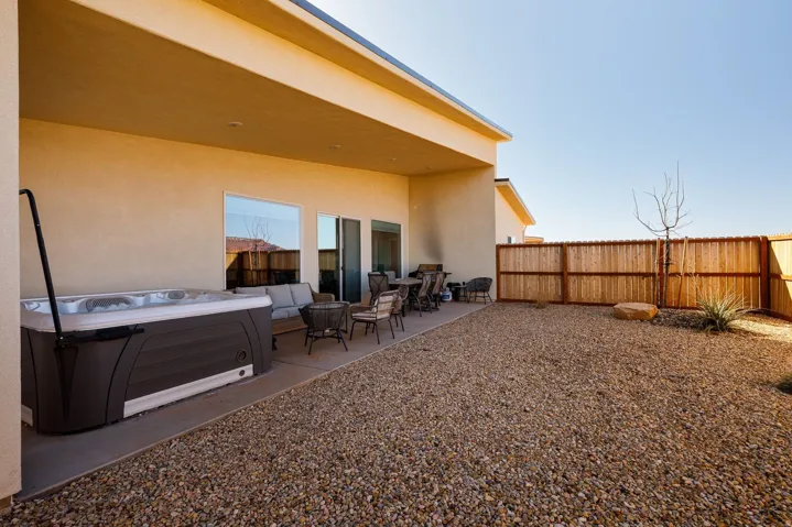 Back of house featuring stucco siding, a patio area, a fenced backyard, and a hot tub