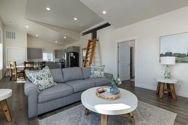 Living room with dark wood finished floors, recessed lighting, and vaulted ceiling