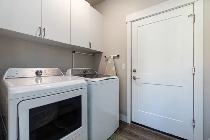 Laundry room with cabinet space, washing machine and dryer, and dark wood finished floors