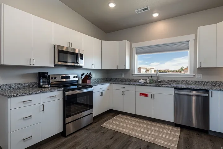 Kitchen with stainless steel appliances, white cabinets, dark stone counters, dark wood-type flooring, and recessed lighting