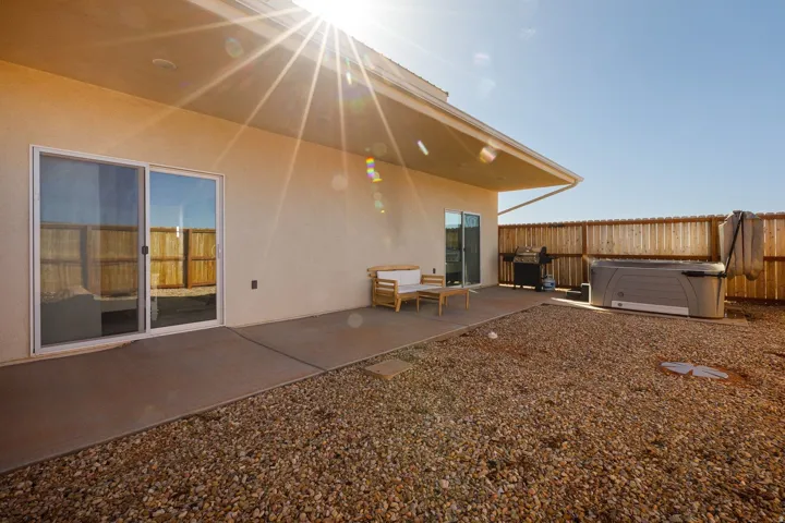 Back of property featuring a patio area, stucco siding, a hot tub, and a fenced backyard