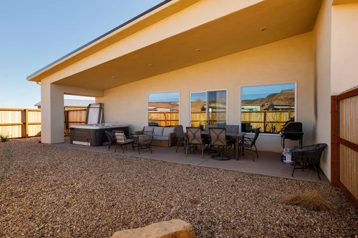Rear view of house featuring a patio area, a fenced backyard, stucco siding, and outdoor dining area