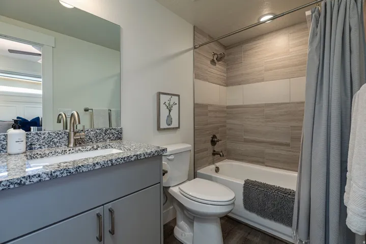 Bathroom with shower / bathtub combination with curtain, vanity, and wood finished floors