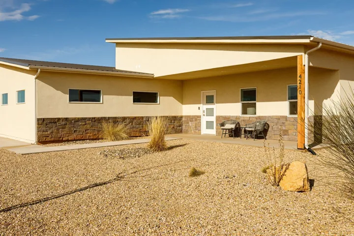Back of house featuring stucco siding, stone siding, and a patio area